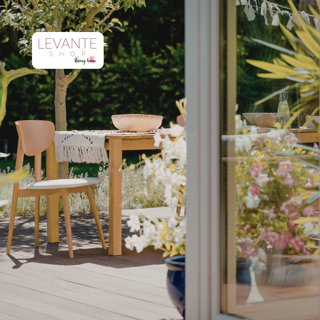 Angolo giardino arredato con tavolo e sedia in legno, circondato da piante e fiori, ideale per un outdoor accogliente e rilassante.