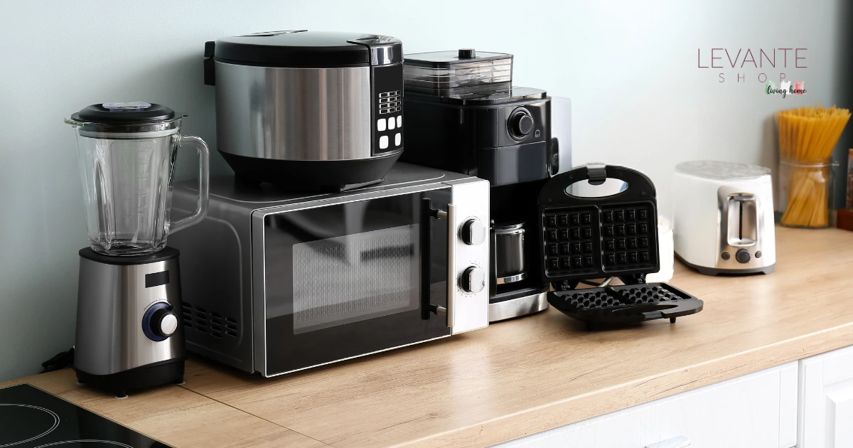 Piano cucina con piccoli elettrodomestici salvaspazio: frullatore, microonde, multicooker, macchina da caffè, piastra per waffle e tostapane in acciaio su top in legno, stile moderno minimal.